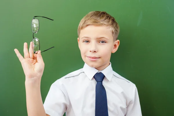 Framgångsrika skolpojke står nära tavlan i skolan klassrum — Stockfoto