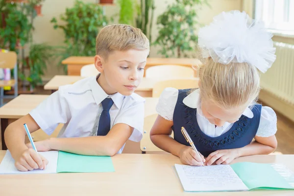 Estudantes ou colegas de classe na sala de aula sentados juntos na mesa — Fotografia de Stock