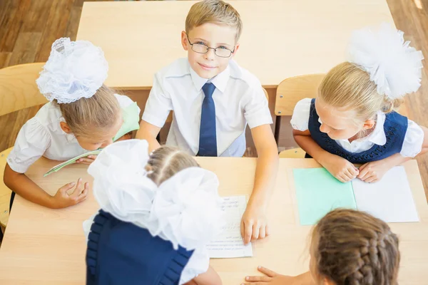 Group of schoolchildren at school classroom sitting at desk — Stock fotografie