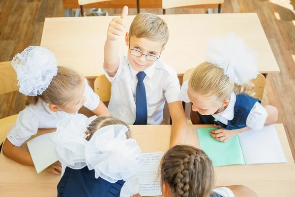 Group of schoolchildren at school classroom sitting at desk — Stockfoto