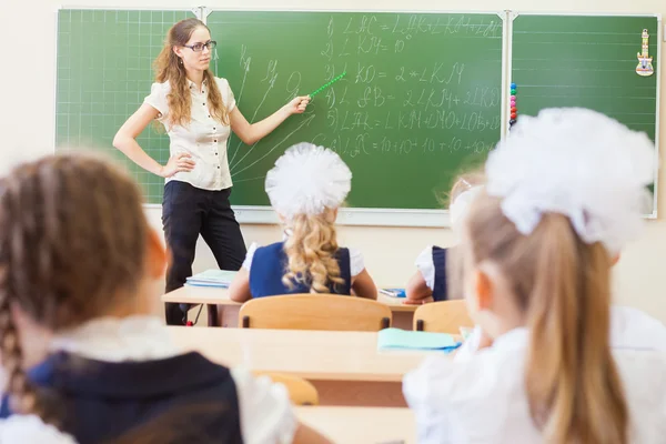 Leraar in de buurt van blackboard onderwijs kinderen math of geometrie, houden van aanwijzer. — Stockfoto