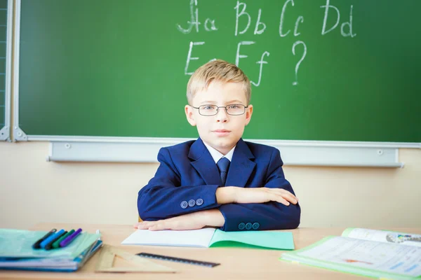 Schoolboy sits at a desk at school classroom — Stok fotoğraf