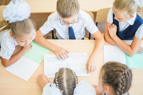 Grupo de escolares en el aula escolar sentados en el escritorio —  Fotos de Stock