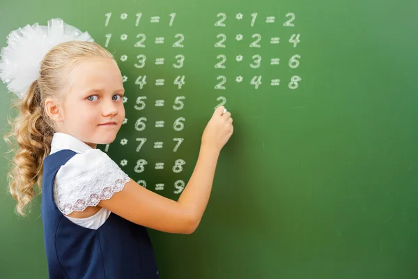 First grade schoolgirl wrote multiplication table on blackboard with chalk — Zdjęcie stockowe