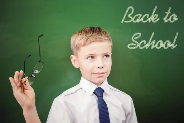 Schoolboy looking to blackboard with text of back to school — ストック写真