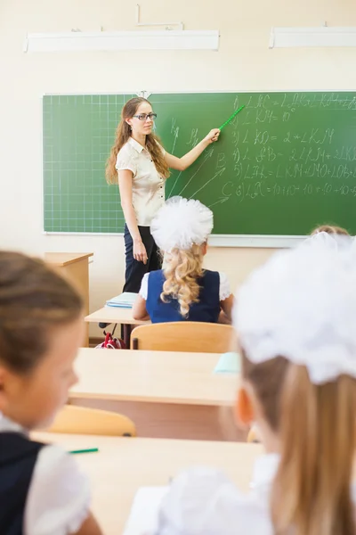 Leraar in de buurt van blackboard onderwijs kinderen math of geometrie, houden van aanwijzer. — Stockfoto