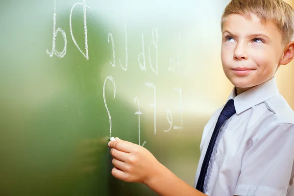 El chico de la escuela escribe alfabeto inglés con tiza en pizarra —  Fotos de Stock