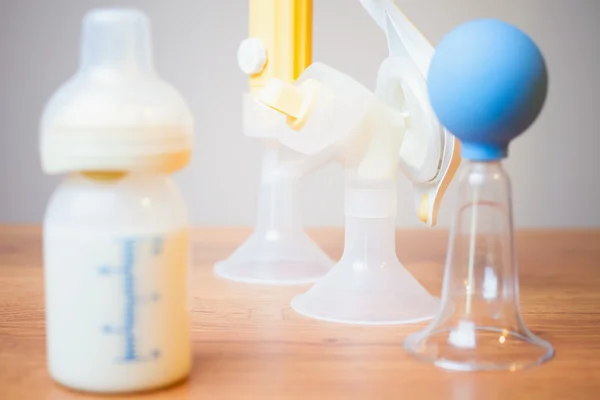 Baby bottle with milk and manual breast pump at background — ストック写真