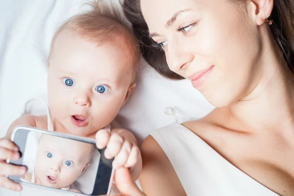 Funny baby girl with mom make selfie on mobile phone — ストック写真