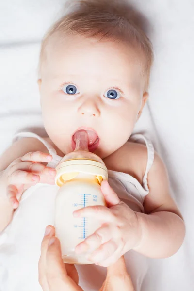 Funny baby holding a bottle with mothers breast milk — Stock Photo, Image