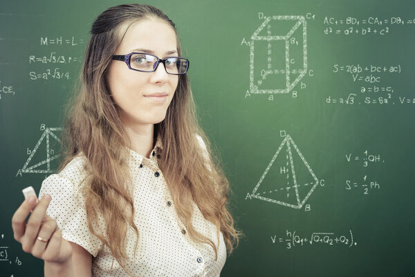 Smart student or teacher drawing mathematic formula at blackboard