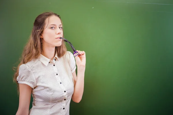 Гарненька вчителька або студент тримає окуляри в класі, університет — стокове фото