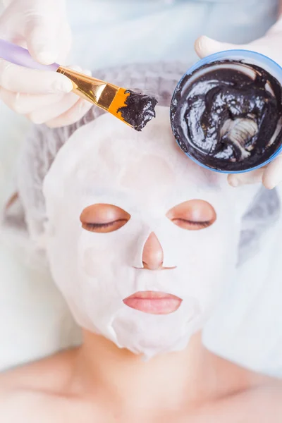 Cosmetologist in spa salon applying mud face mask using brush — Stock Photo, Image