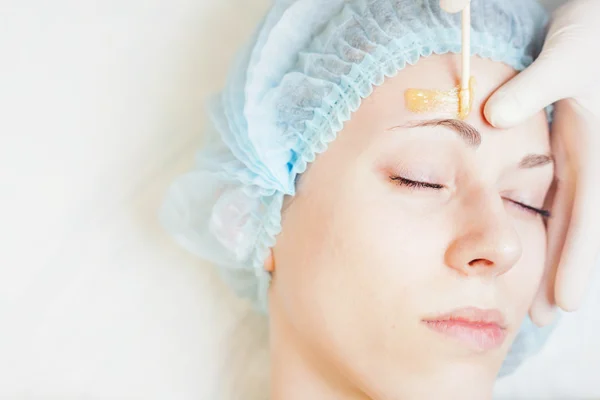 Hermosa mujer en el salón de spa recibiendo depilación o corrección de cejas —  Fotos de Stock