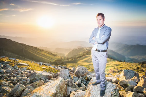 Úspěšný podnikatel na vrcholu hory při pohledu na fotoaparát — Stock fotografie