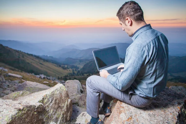 Εικόνα ενός επιχειρηματία στην κορυφή του βουνού, χρησιμοποιώντας ένα φορητό υπολογιστή — Φωτογραφία Αρχείου