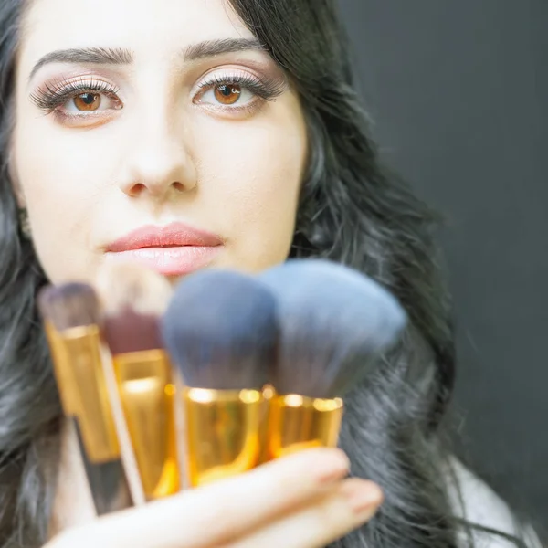 Beautiful woman at beauty salon with set of makeup brushes — Stock Photo, Image