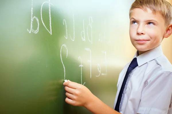 学校男孩写英文字母用粉笔在黑板上 免版税图库照片