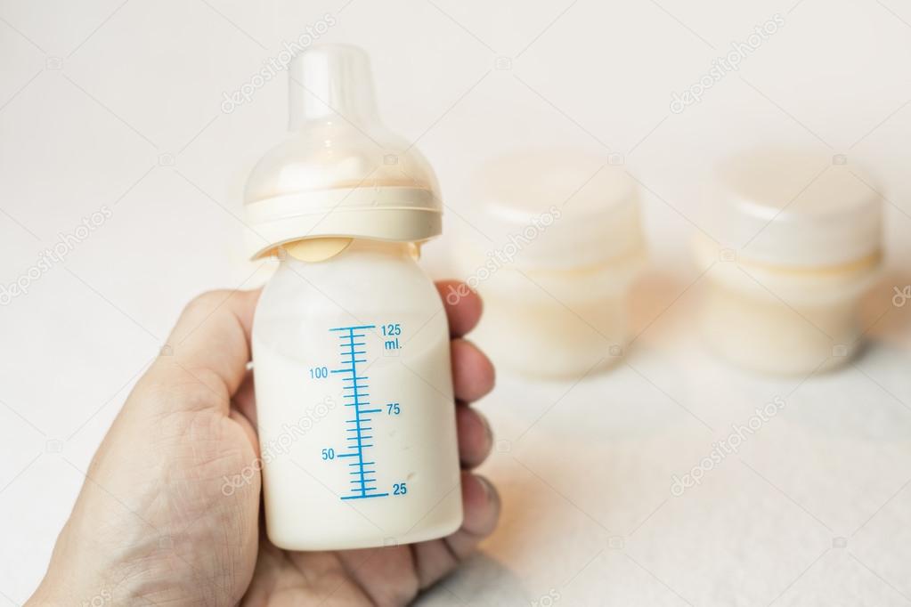 Father holding a baby bottle with breast milk with scale