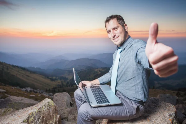 Empresário de sucesso no topo da montanha, usando um laptop — Fotografia de Stock