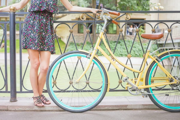 Chica joven de pie cerca de la cerca cerca de la bicicleta vintage en el parque — Foto de Stock