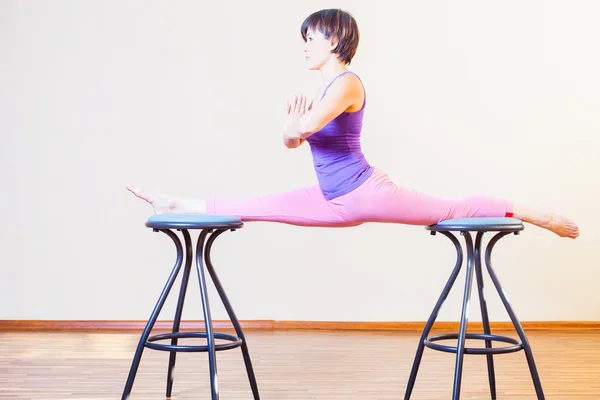 Asian woman stretching for yoga exercise at home by chairs