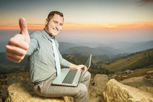 Hombre de negocios exitoso en la cima de la montaña, utilizando un ordenador portátil — Foto de Stock