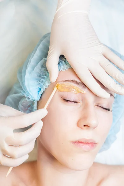 Beautiful woman in spa salon receiving epilation or correction eyebrow — Stock Photo, Image