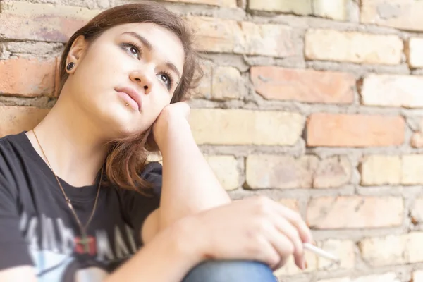 Schoolmeisje tiener rookt buiten op stenen muur achtergrond — Stockfoto