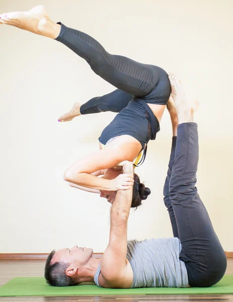 Man och kvinna gör acro yoga eller par yoga inomhus — Stockfoto