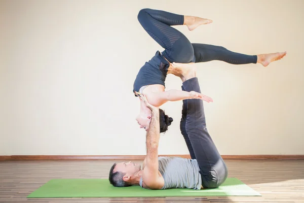 Man och kvinna gör acro yoga eller par yoga inomhus — Stockfoto