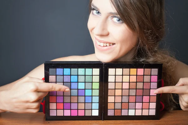 Гламурная женщина указывает на красочную палитру для макияжа — стоковое фото