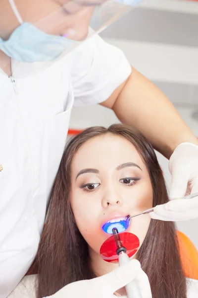 Médico dentista trata dentes paciente menina no consultório odontológico — Fotografia de Stock