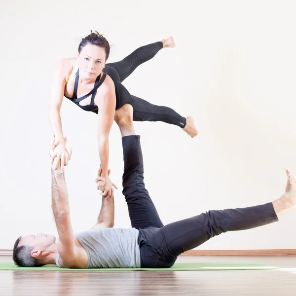 Pria dan wanita melakukan acro yoga atau pasangan yoga di dalam ruangan — Stok Foto