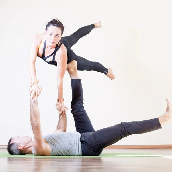 Man och kvinna gör acro yoga eller par yoga inomhus — Stockfoto