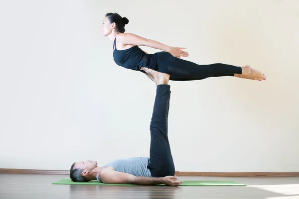 Man and woman doing acro yoga or pair yoga indoor — Stock Photo, Image