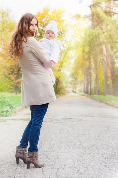 Moda mãe andando com seu bebê ao ar livre no parque de outono — Fotografia de Stock