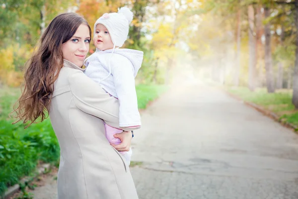 Модна мати йде з дитиною на відкритому повітрі в осінньому парку — стокове фото