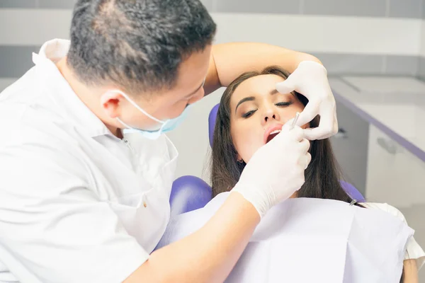 Dentista medico tratta denti paziente ragazza in studio dentistico — Foto Stock