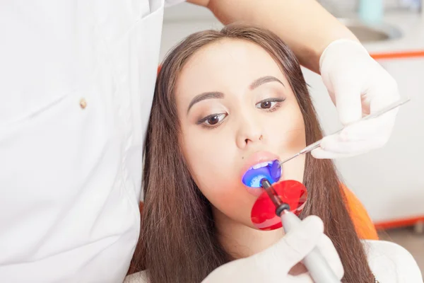 Dentista medico tratta denti paziente ragazza in studio dentistico — Foto Stock