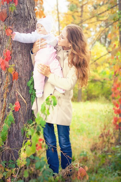 Moda mãe andando com seu bebê ao ar livre no parque de outono — Fotografia de Stock