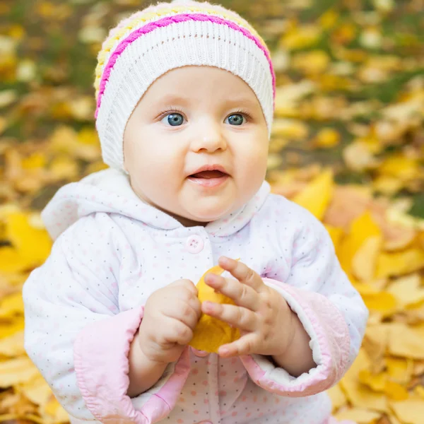 Happy baby outdoor at autumn park playing with yellow leaves — Stock Photo, Image