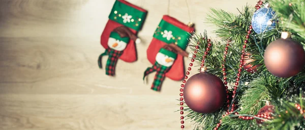Decorated red ball on Christmas tree with socks at background — Stock fotografie