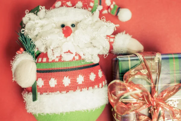 Caixa de presente de Natal com brinquedo Papai Noel no fundo vermelho — Fotografia de Stock