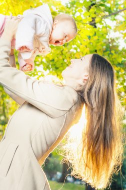 Happy mother with her baby girl outdoor at autumn park