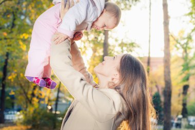 Happy mother with her baby girl outdoor at autumn park