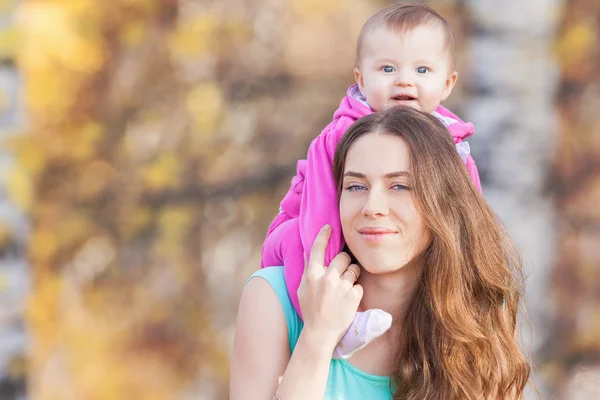 Happy child and beautiful mother outdoor at autumn park — Stock Photo, Image