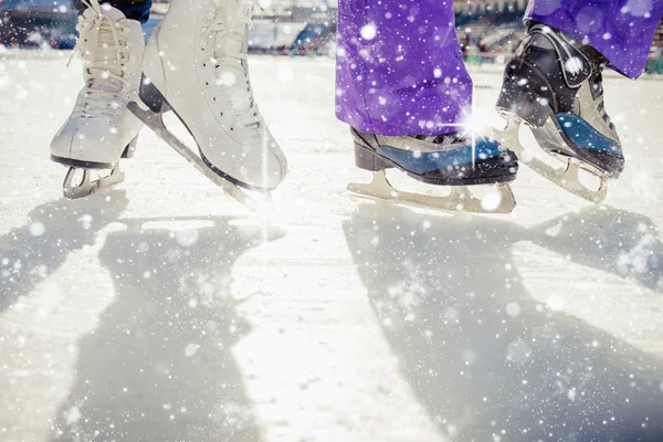 Pair is placed on ice skating. It is snowing outside