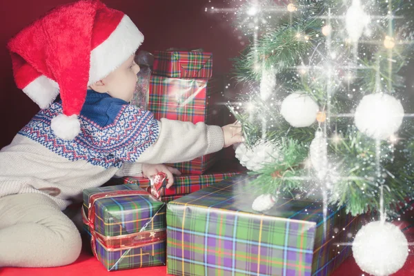 Gelukkig baby in de buurt van gedecoreerde kerstboom met vele doos van de gift — Stockfoto