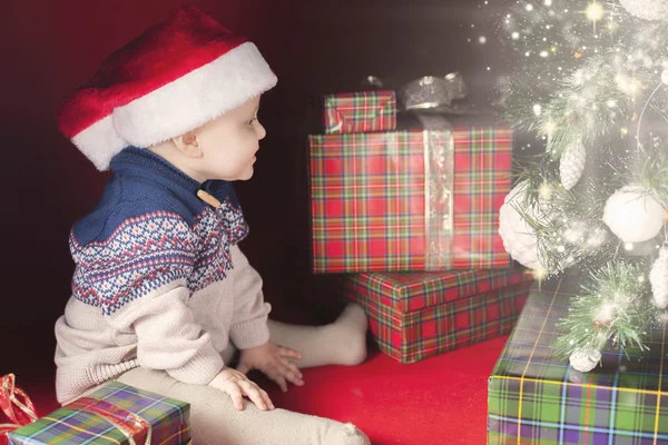 Gelukkig baby in de buurt van gedecoreerde kerstboom met vele doos van de gift — Stockfoto